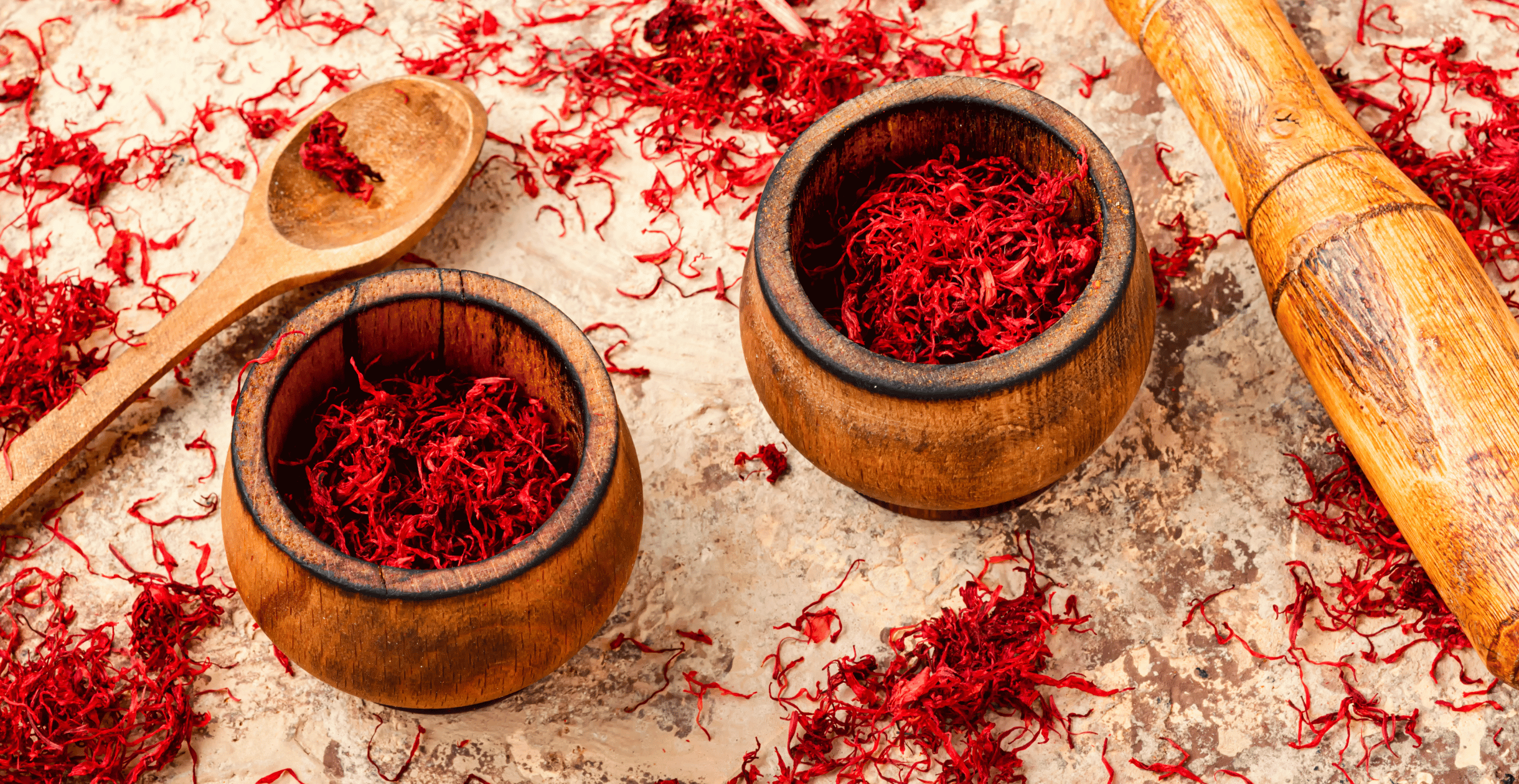 Close-up of saffron threads in wooden bowls with a spoon and pestle